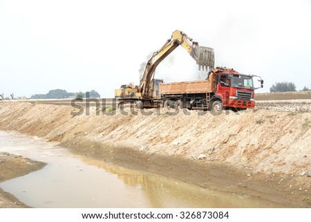 Wheel loader Excavator with backhoe loading sand into lorry
