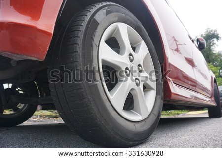 Close up of a black car tyre park on the road. View from bottom of car.