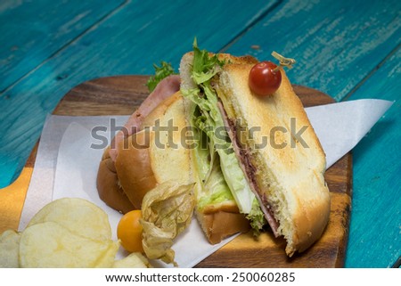 Ham salad sandwich serving with potato chips on wood plate
