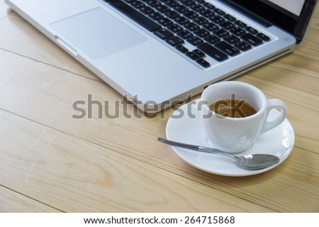 a cup of espresso coffee and computer on wooden table background
