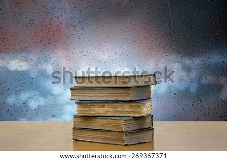 Old books stack on rain drop and blue bokeh abstract background