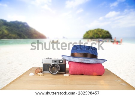 Idea concept. Red pink tower, blue hat, old vintage camera and shells over wooden floor on sunshine blue sky and ocean background.