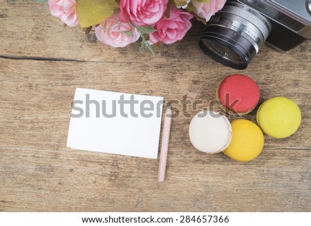 Empty note paper ,macaroons flower and vintage camera on wooden background