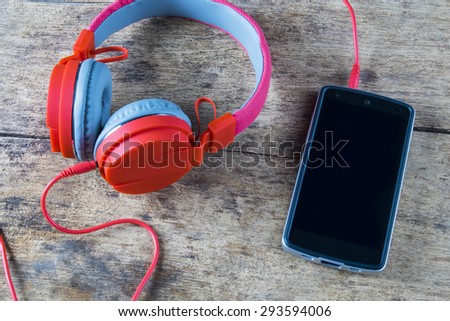 Mobile phone connecting with red headphone over the keyboard.Vintage color style.