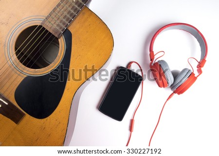 Relaxing time. Red earphone on guitar connect with smart phone.