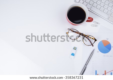 View from above of office supplies and red cup of coffee on a white working table background.