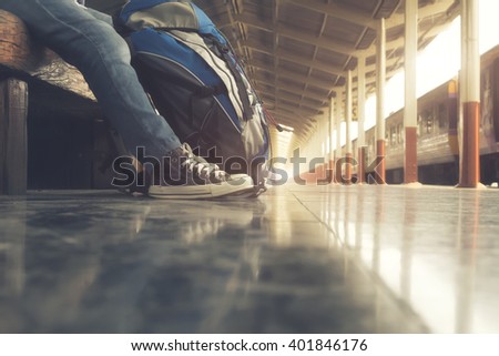 Traveler wearing backpack waiting for a train at train station and planing for next trip.Vintage tone, Retro filter effect, Soft focus, Low light.(selective focus)