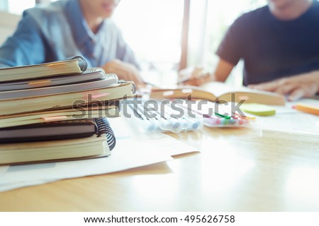 Young woman and man studying for a test/ an exam. Tutor books with friends. Young students campus helps friend catching up and learning. People, learning, education and school concept.