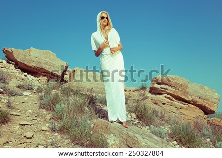 Blonde woman in sunshine rays in sunglasses under hot sun. Summer day. Hot weather. Caravan. Summer wind. Summer sky. Blue sky girl. White clothes.