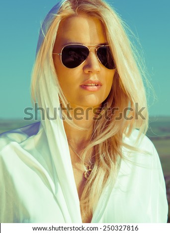 Blonde girl in sunshine rays in sunglasses under hot sun. Summer day. Hot weather