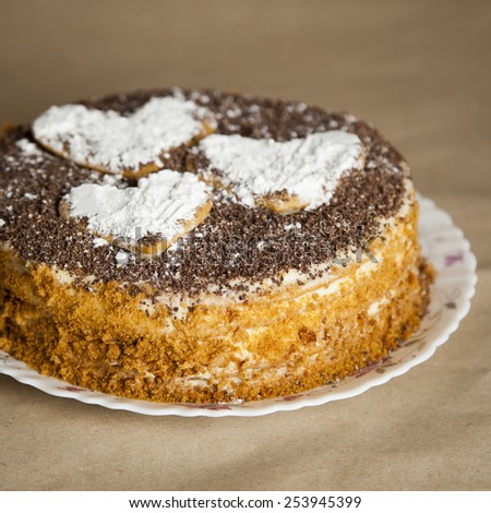 cake with chocolate crumb. Honey cake. Cake hearts. Cake on warm background. Cake on white plate. Baked cake. White powder cake. Dish cake. Bake food. Baking