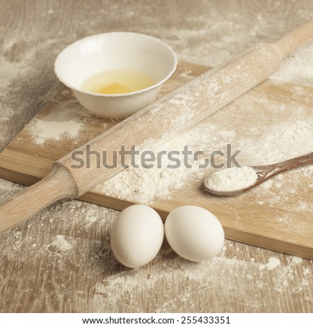 Baking. Preparations for homemade baking. Basic ingredients for baking. Kitchen utensil with eggs rolling-pin wood spoon meal. Meal on table with cutting board. Flour