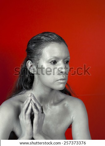 Silver woman face with ring, bijou on red background. Strange kind of woman. Fashion