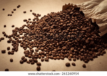 Coffee beans on paper background. Paper texture coffee. Dark coffee roasted. Coffee beans. Bag of coffee, spill
