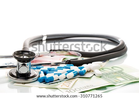 Euro bills with stethoscope and pills on a white table