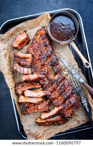 Barbecue spare ribs St Louis cut with hot honey chili marinade as top view in a rustic skillet on backing paper
