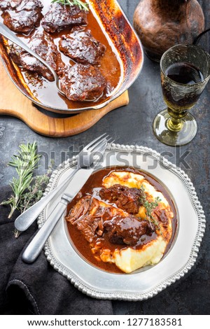 Traditional German braised veal cheeks in brown sauce with mashed potatoes as top view on a pewter plate