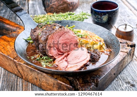 Barbecue roast boar joint with roesti and game red wine sauce as top view in a wrought-iron pan
