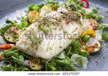 Fried cod fish fillet with lettuce and vegetable as close-up on a plate