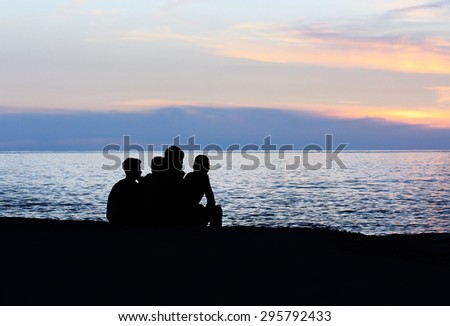 Silhouettes of boys sitting on the coast and looking on the sea in the evening. Location Alanya, Turkey.