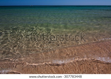 Crystal transparent waves going on the sand beach. Location Pinus Village, Sardinia.