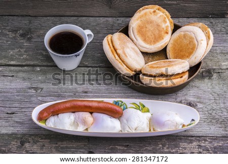 Protein rich breakfast with four eggs Benedict and Viennese sausage with toasted muffins and a cup of coffee.