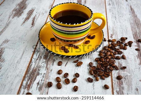 Coffee cup with coffee beans on the old light wooden background