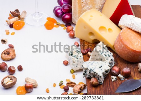 Cheeses with dried fruits and nuts on wooden board