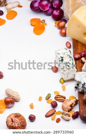 Cheeses with dried fruits and nuts on wooden board