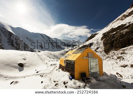 Simple mountain shelter in a snow valley, Altai mountains, Russia