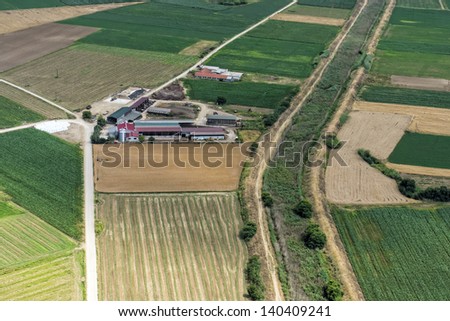 Aerial view of a small cow farm, in the middle of green agricultural area