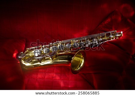 Saxophone on a red background. Magical glow of tool, magnificent tenor saxophone.
