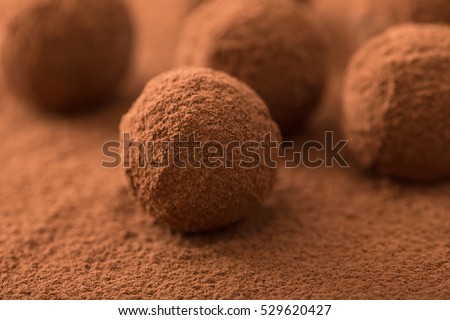 Close up of group of appetizing black chocolate truffles covered in cocoa dust. Shallow depth of field