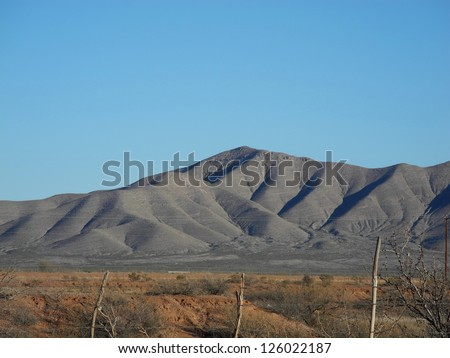 Scenic view of the Van Horn mountain range in Texas, with grassland and brush in the mid-ground.