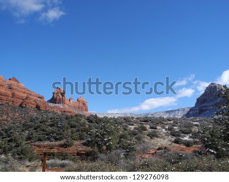 The rugged landscape around scenic Sedona, Arizona, offers lush trees and brush and dramatic mesas, cliffs and monuments.  Here the red rock hills and vegetation are frosted with snow.
