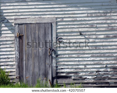 Weathered side of barn with plank door and horseshoe.