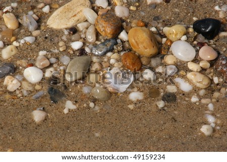 Pebbles of different colors and sizes, make a rock constellation on the shore.