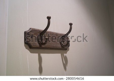 Old iron hooks on wooden rack attached on the wall.