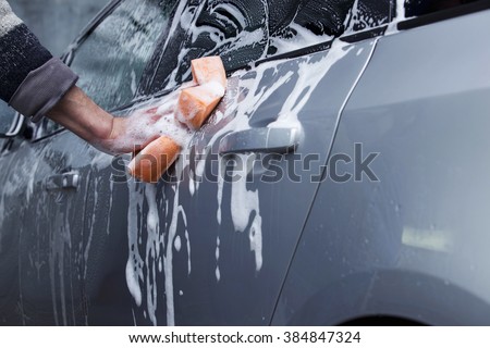 a silver car is washing in soap suds