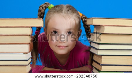 face of the schoolgirl of 9 years. On the right and at the left piles of books. A photo on a blue background