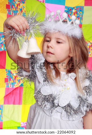 The girl in a New Year\'s dress looks at a fur-tree`s  toy