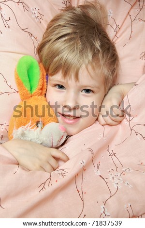 Happy kid trying to sleep with a favorite toy