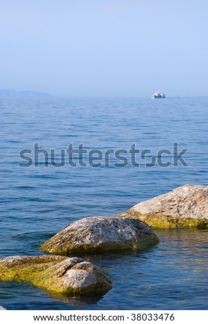 Stones sticking out of water, the ship on a background