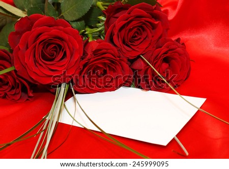 Red roses and invitation card on silk background