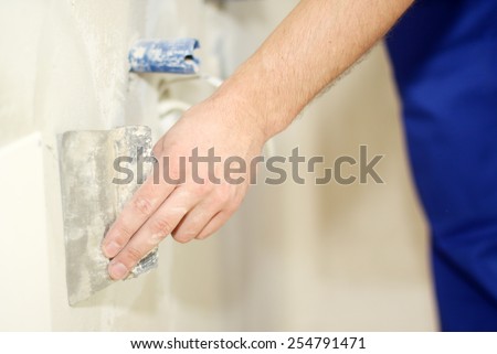 Man hand with trowel plastering a wall, skim coating plaster walls