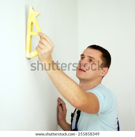 Male plasterer in uniform polishing the wall