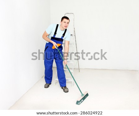 Young man cleaning floor with brush after repair