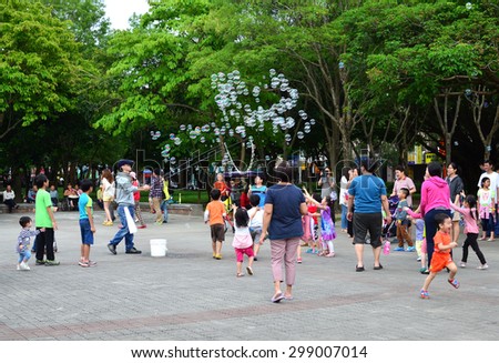 New taipei City, Taiwan- 26 April , 2015: A man blowing soap bubbles to attract people in the park