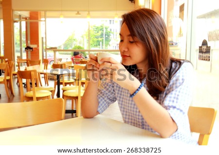 asia girl hold cup of coffee in hand look in window