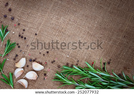 Fresh rosemary, garlic and black pepper on sackcloth background